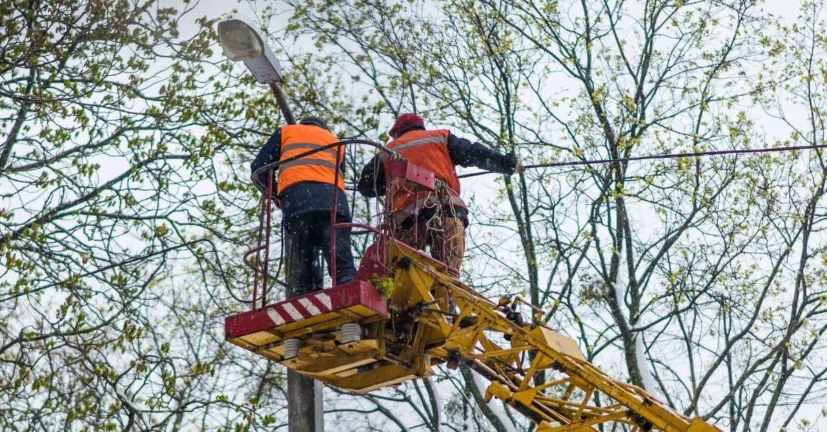 Utility worker in a cherry picker repairing power lines