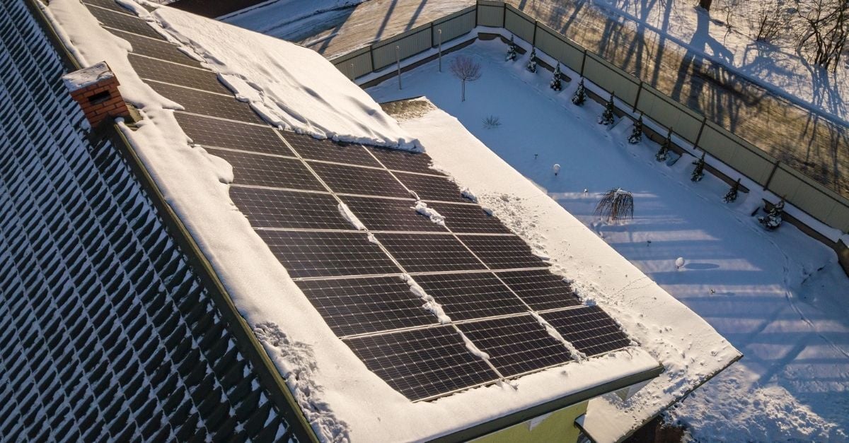 House roof covered with solar panels in winter with snow